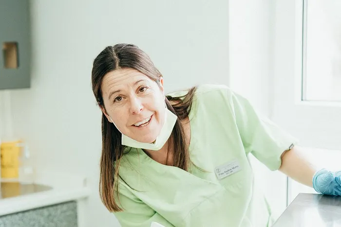 Eine Assistentin lächelt im Behandlungszimmer in die Kamera