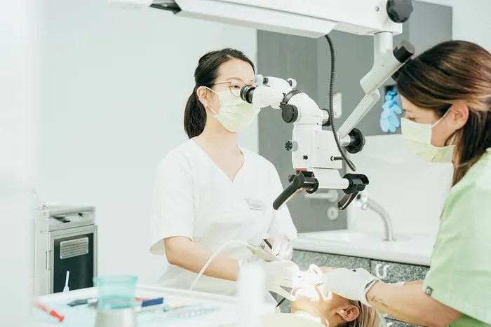 Dr. Jiang und eine Assistentin bei der Behandlung am OP-Mikroskop
